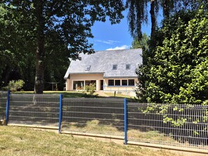 A house with a sloped roof, a fenced yard, and a large tree in the foreground. - Pet-friendly Country House in Central Brittany (Saint-Vran)