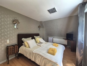 A bedroom with a bed, bedside lamps, a TV, and a wooden floor. - Pet-friendly Country House in Central Brittany (Saint-Vran)