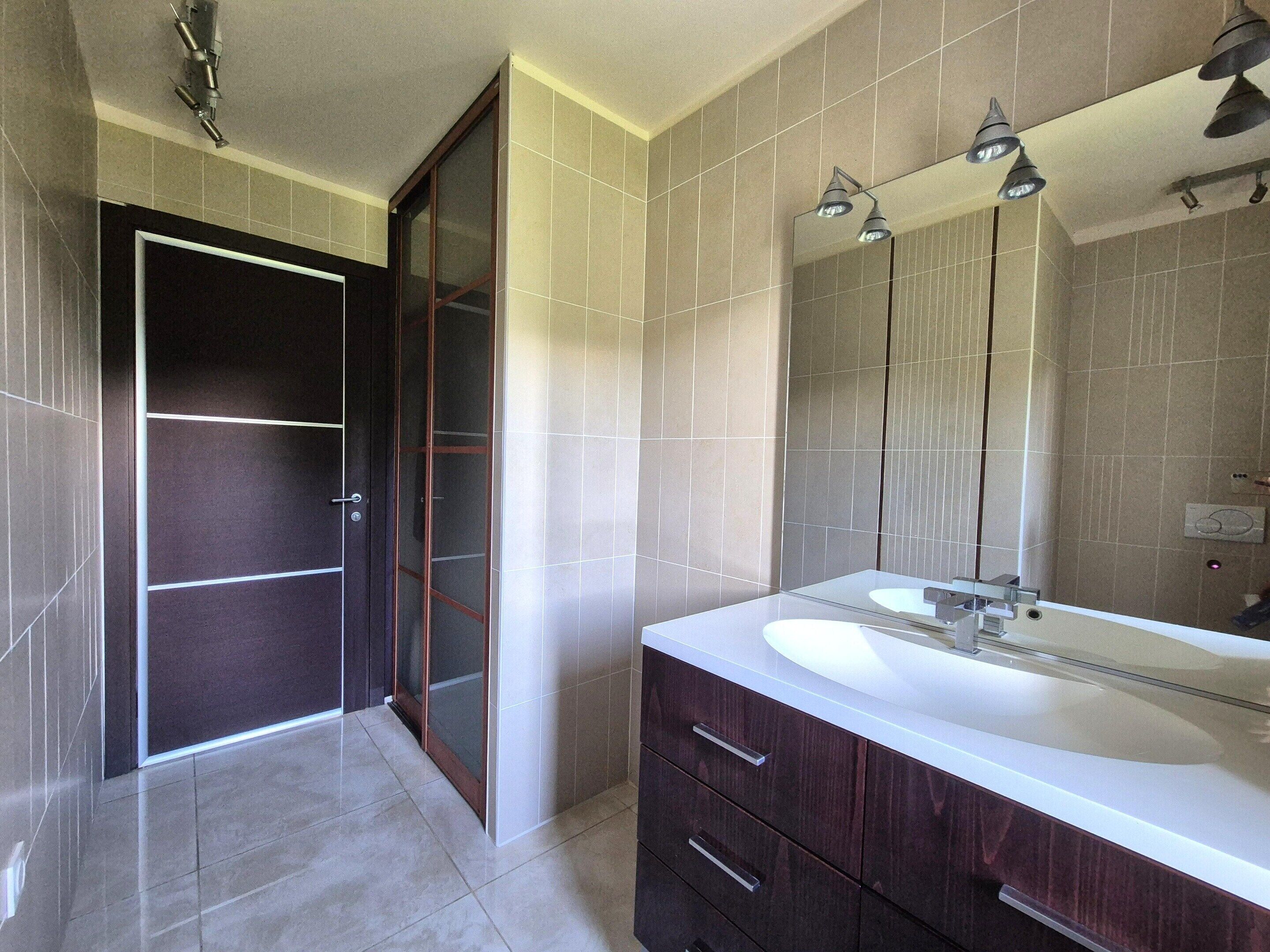 Een badkamer met een grote spiegel, een wastafel en een douche.