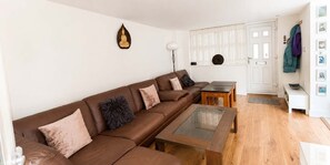 Ein modernes Wohnzimmer mit einem braunen Ledersofa, einem Couchtisch mit Glasplatte und einer weißen Tür mit Fenster.