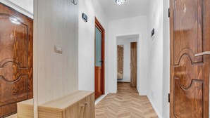 A hallway with wooden flooring, a bench, and two wooden doors.