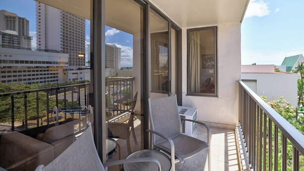 Ein Balkon mit Gartenmöbeln, Blick auf die Stadt und ein Gebäude mit einer Dachbegrünung.