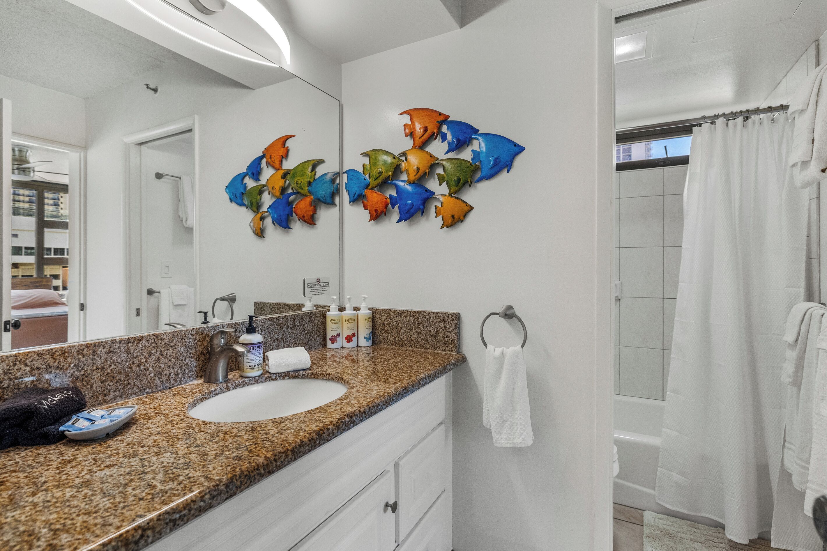 A bathroom with a granite countertop, a sink, a mirror, and a shower curtain.