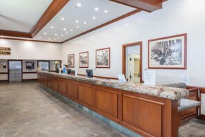 A reception desk with a marble top, wooden paneling, and framed black and white photographs on the wall. - Waikiki Banyan Corner Unit w/ In-Unit W/D & Parking (Honolulu)
