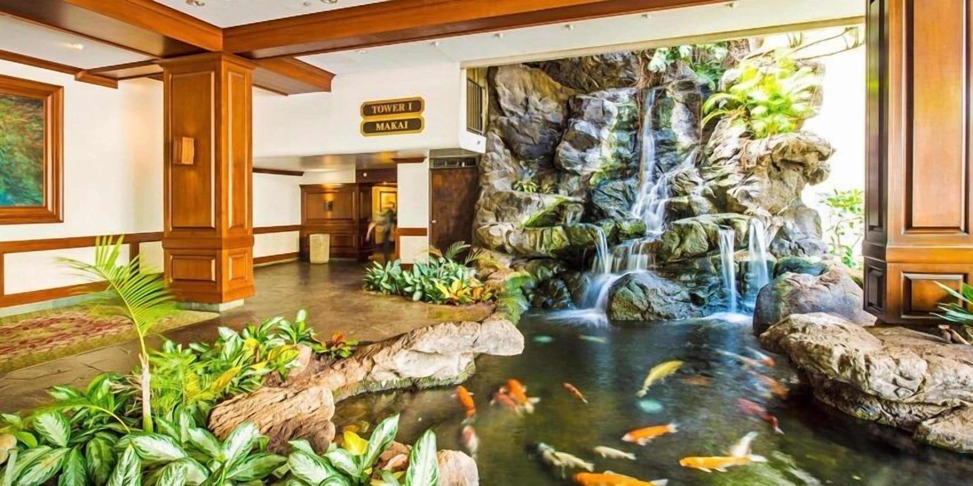 Un vestíbul amb un estany de carps koi, una cascada i un cartell que diu 'Tower 1 Marai'.