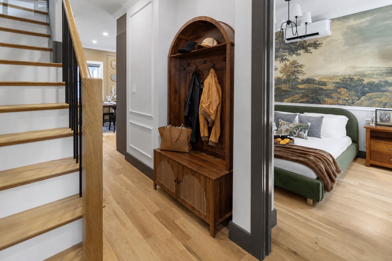 A bedroom with a bed, a nightstand, a dresser, and a coat rack.