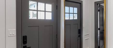 A room with two doors, one with a window, and a large mirror with a gold frame.