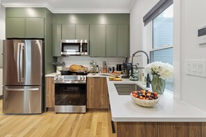 Una cocina moderna con electrodomésticos de acero inoxidable, una isla de madera y un ventanal amplio.
