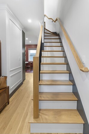 Una escalera de madera con barandilla que sube a un piso superior.