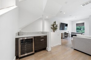 A modern kitchen with a built-in oven, a dining area with a grey sofa, and a large window providing a view of greenery. - Luxury Houston home located in Houston prime location (Houston)
