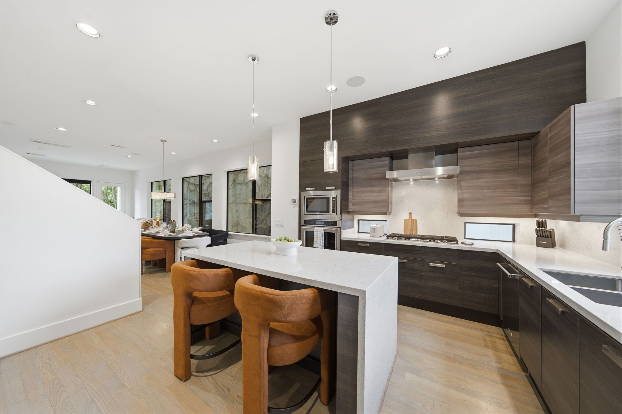 A modern kitchen with dark wood cabinets, a central island with bar stools, and stainless steel appliances.