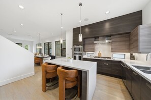 A modern kitchen with dark wood cabinets, a central island with bar stools, and stainless steel appliances. - Luxury Houston home located in Houston prime location (Houston)