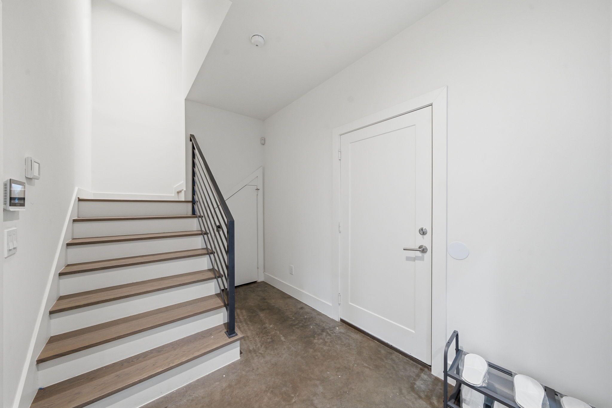 A staircase with wooden steps and a metal railing leading to a white door.