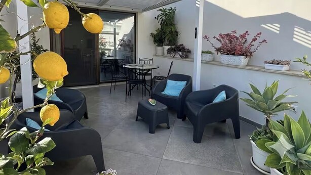 An outdoor seating area with chairs and tables, surrounded by potted plants and a pergola. - "La Brogna" Apartment - Downtown Mazara del Vallo (Mazara del Vallo)