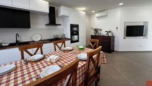 A modern kitchen with white cabinets, a black range hood, and a dining area with a checkered tablecloth. - "La Brogna" Apartment - Downtown Mazara del Vallo (Mazara del Vallo)