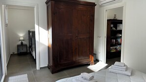 A bedroom with a large wardrobe, a bedside table with a lamp, and a neatly made bed. - "La Brogna" Apartment - Downtown Mazara del Vallo (Mazara del Vallo)
