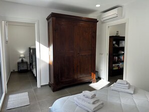 A bedroom with a large wardrobe, a bedside table with a lamp, and a neatly made bed. - "La Brogna" Apartment - Downtown Mazara del Vallo (Mazara del Vallo)