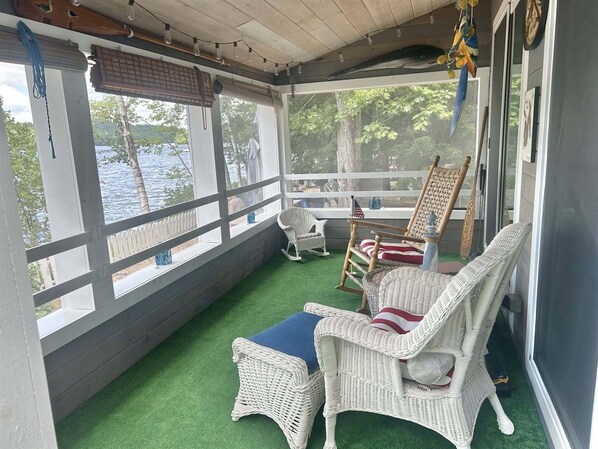 A covered porch with wicker furniture, a view of the water, and a clock on the wall.