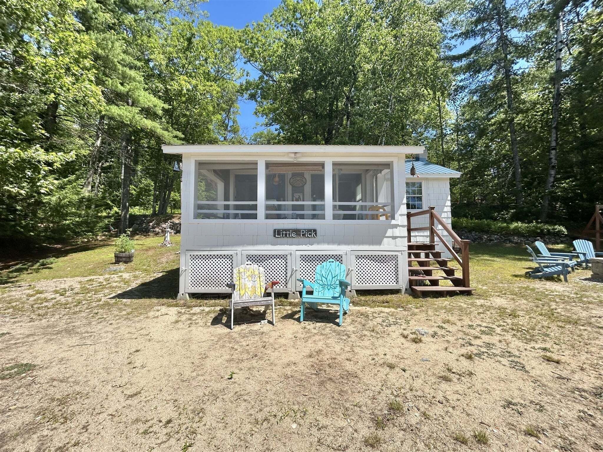 A cabin with a covered porch, a staircase, and outdoor seating.
