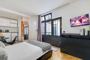 A modern hotel room with a bed, a small kitchen area, a dining table, and a large window. - Charming Studio 2P - Canal Saint Martin (Paris)