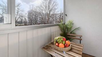 A balcony with a wooden bench and a wicker basket containing fruits and vegetables.