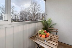Uma varanda com um banco de madeira e uma cesta de vime com frutas e legumes.