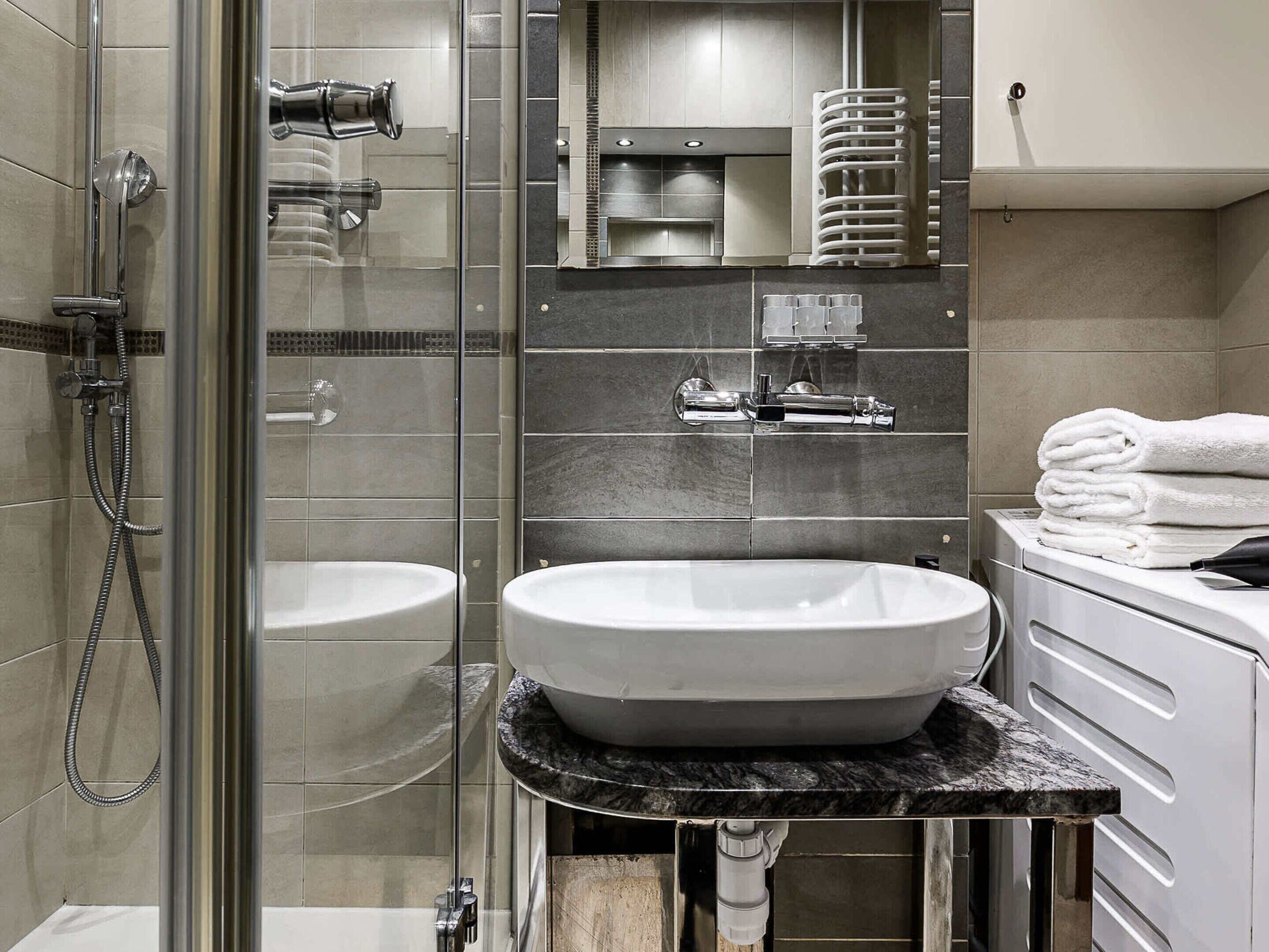 Une salle de bain moderne avec une douche à parois de verre, deux vasques et un comptoir en marbre.