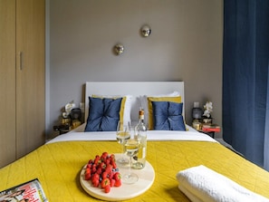 Ein Hotelzimmer mit einem Bett, einem Nachttisch mit Lampe, einem Beistelltisch und einer Wandleuchte.