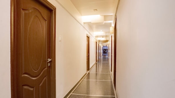 Un couloir d’hôtel avec des portes en bois, un sol carrelé et un mur de couleur claire.