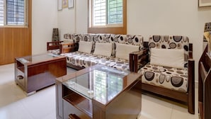 Un salon moderne avec un ensemble de canapés, une table basse en verre et un téléviseur à écran plat fixé au mur.