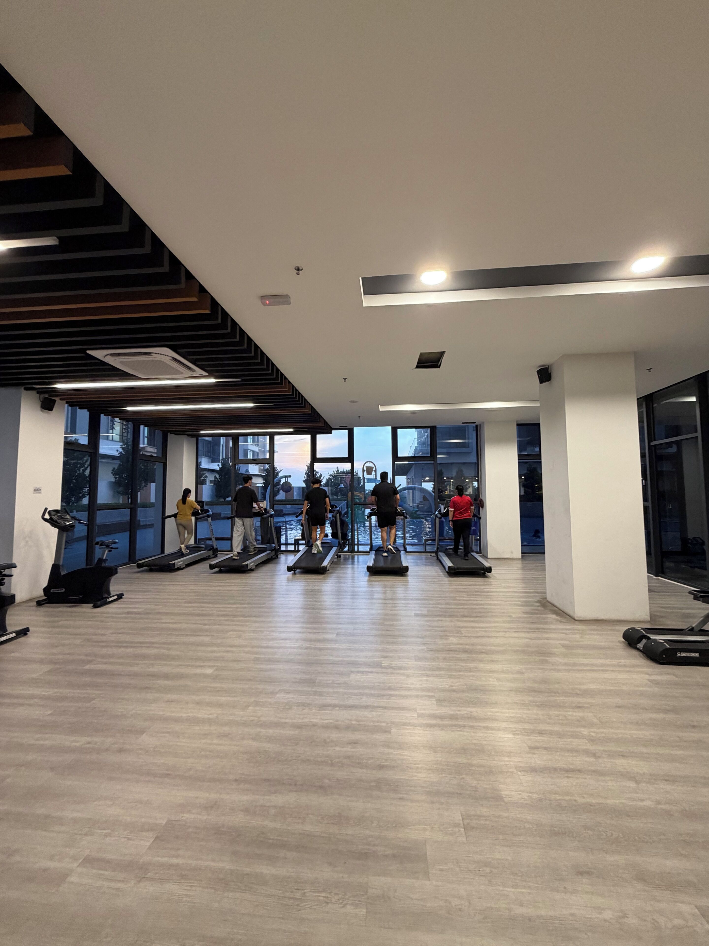 Un gimnasio con cintas de correr, bicicletas estáticas y un amplio ventanal con vistas al agua.