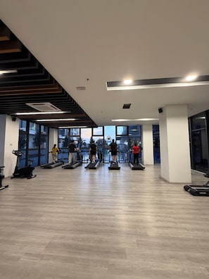 A gym with treadmills, exercise bikes, and a large window overlooking a body of water.