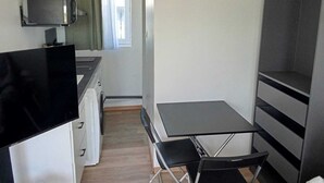 A compact kitchenette with a small table and chairs, a television, and a wardrobe.