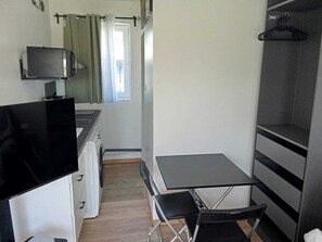 A compact kitchenette with a small table and chairs, a television, and a wardrobe.
