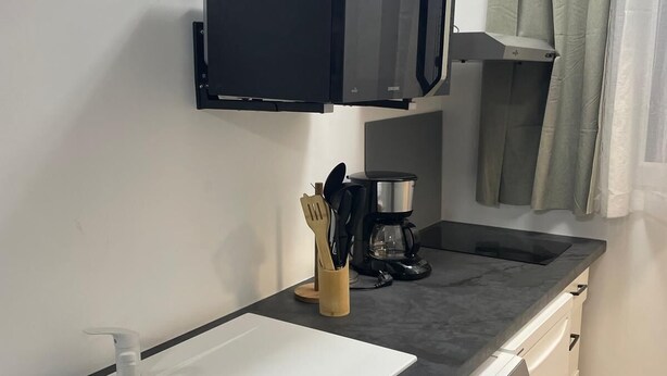 A compact kitchenette with a microwave, coffee maker, and a sink.