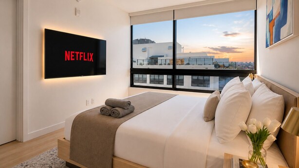 A modern bedroom with a large bed, a TV mounted on the wall, and a view of the cityscape through the window. - Modern 1BR Stay Near Brickell & Downtown Miami (Miami)