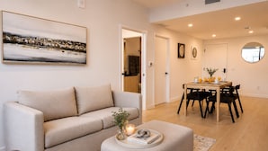 A living room with a sofa, a dining table with chairs, and a coffee table with books and a candle. - Modern 1BR Stay Near Brickell & Downtown Miami (Miami)