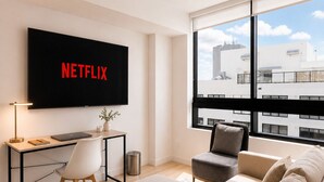 A modern living room with a large window, a flat-screen TV, a desk, and a sofa. - Modern 1BR Stay Near Brickell & Downtown Miami (Miami)