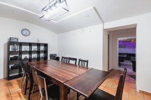 Ein Essbereich mit einem Holztisch und Stühlen, einer schwarzen Regaleinheit mit Gläsern sowie einer Wanduhr.