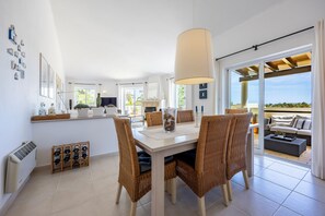 Eine moderne Küche mit Essbereich, großen Fenstern und Blick ins Freie.