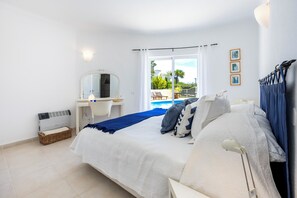 Ein Schlafzimmer mit Bett, Schreibtisch, Stuhl, Spiegel und Blick auf einen Außenpool.