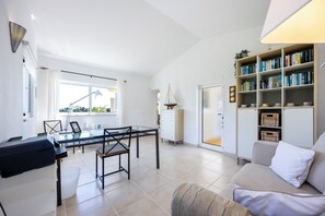 Ein modernes Wohnzimmer mit einem Glastisch, einer Couch und einem Bücherregal voller Bücher.