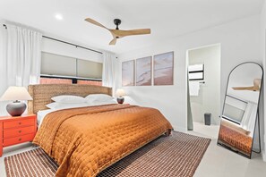 Una camera da letto moderna con un letto, una ventola a soffitto, uno specchio e opere d'arte alle pareti.