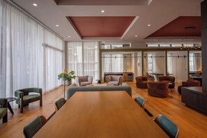 Une salle de conférence spacieuse, dotée d’une grande table en bois, de plusieurs chaises et d’un coin salon avec des canapés et des fauteuils.