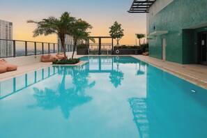 A rooftop swimming pool with a clear view of the city skyline, surrounded by palm trees and modern architecture. - Modern 1BR with Pool Near Brickell & Downtown Miami (Miami)