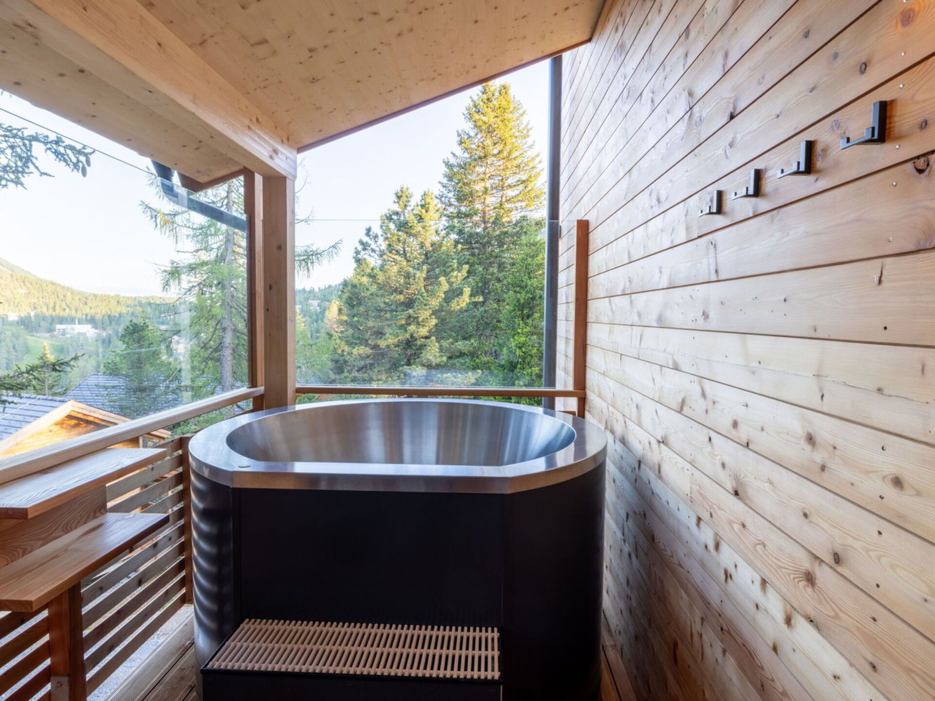 Une salle de bain moderne avec une baignoire sur pieds, des murs en bois et une vue sur un paysage boisé.