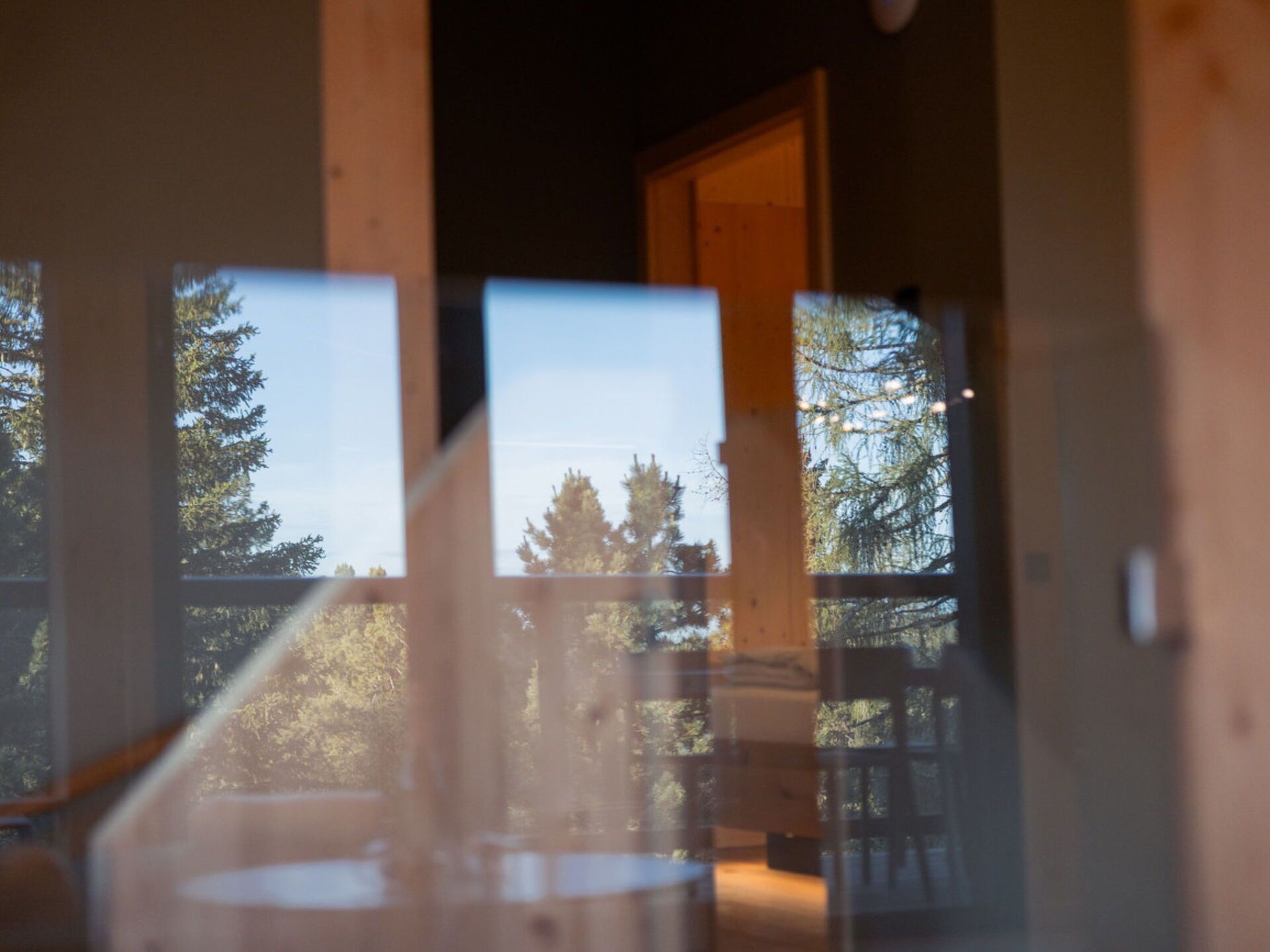 A room with a large window, wooden walls, and a view of trees.