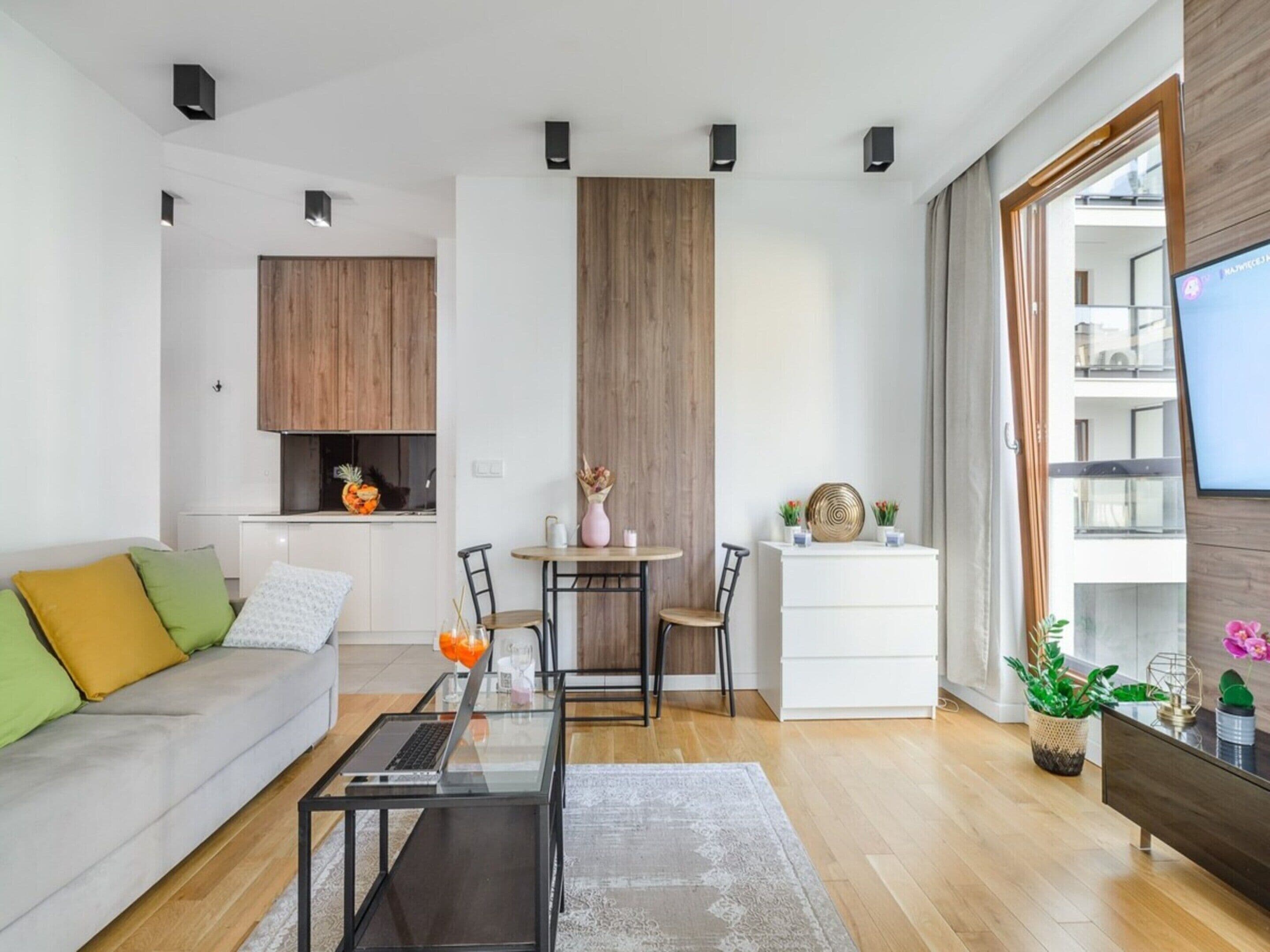 Un saló modern amb un sofà, una taula de centre i una zona de dinar amb cadires i una taula petita.