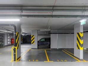 A parking garage with marked parking spaces, an exit sign, and a fire extinguisher. - Warsaw Flat With Quiet Loggia (Warsaw)