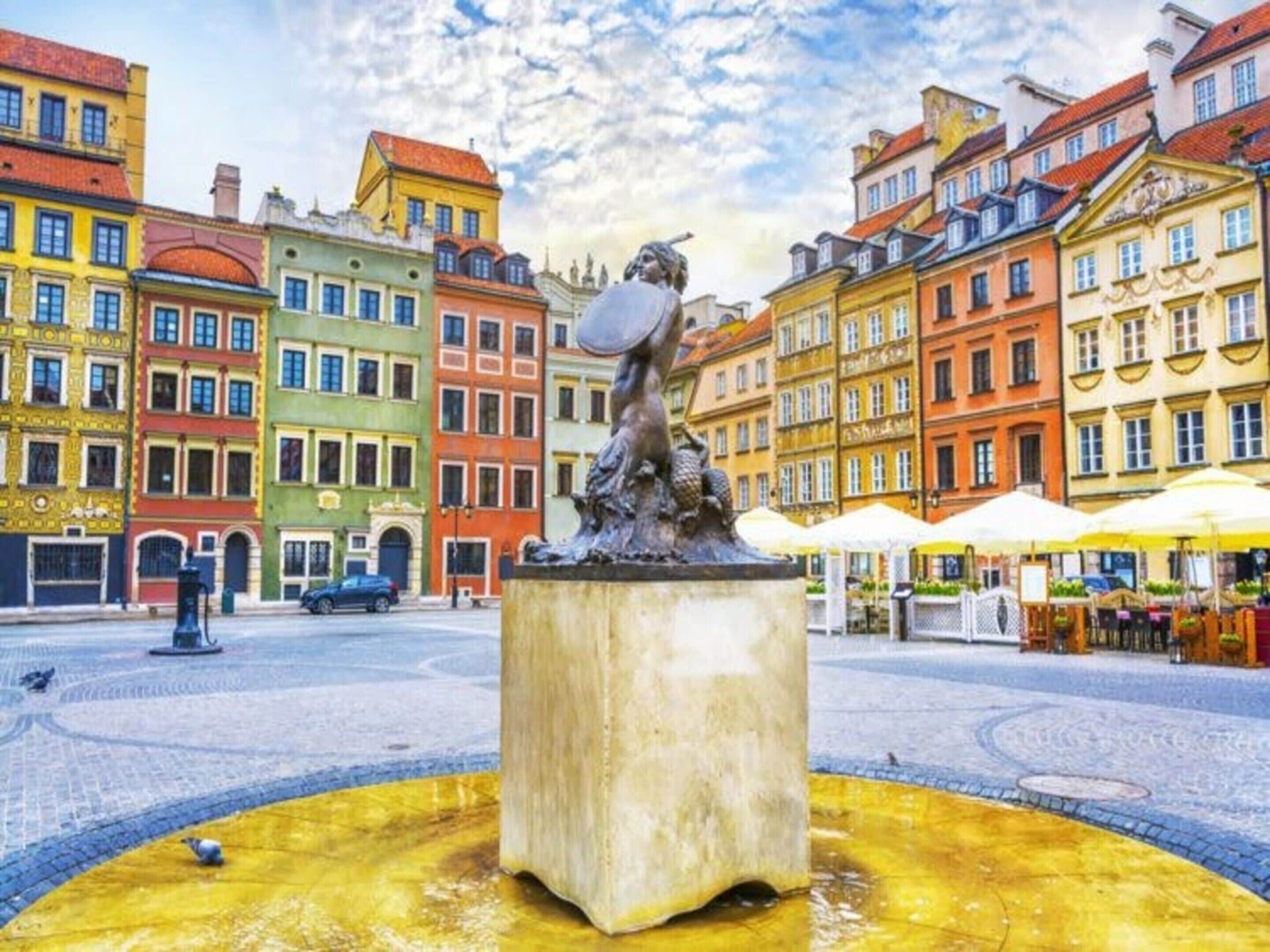 Ein öffentlicher Platz mit einer zentralen Statue, umgeben von bunten Gebäuden.